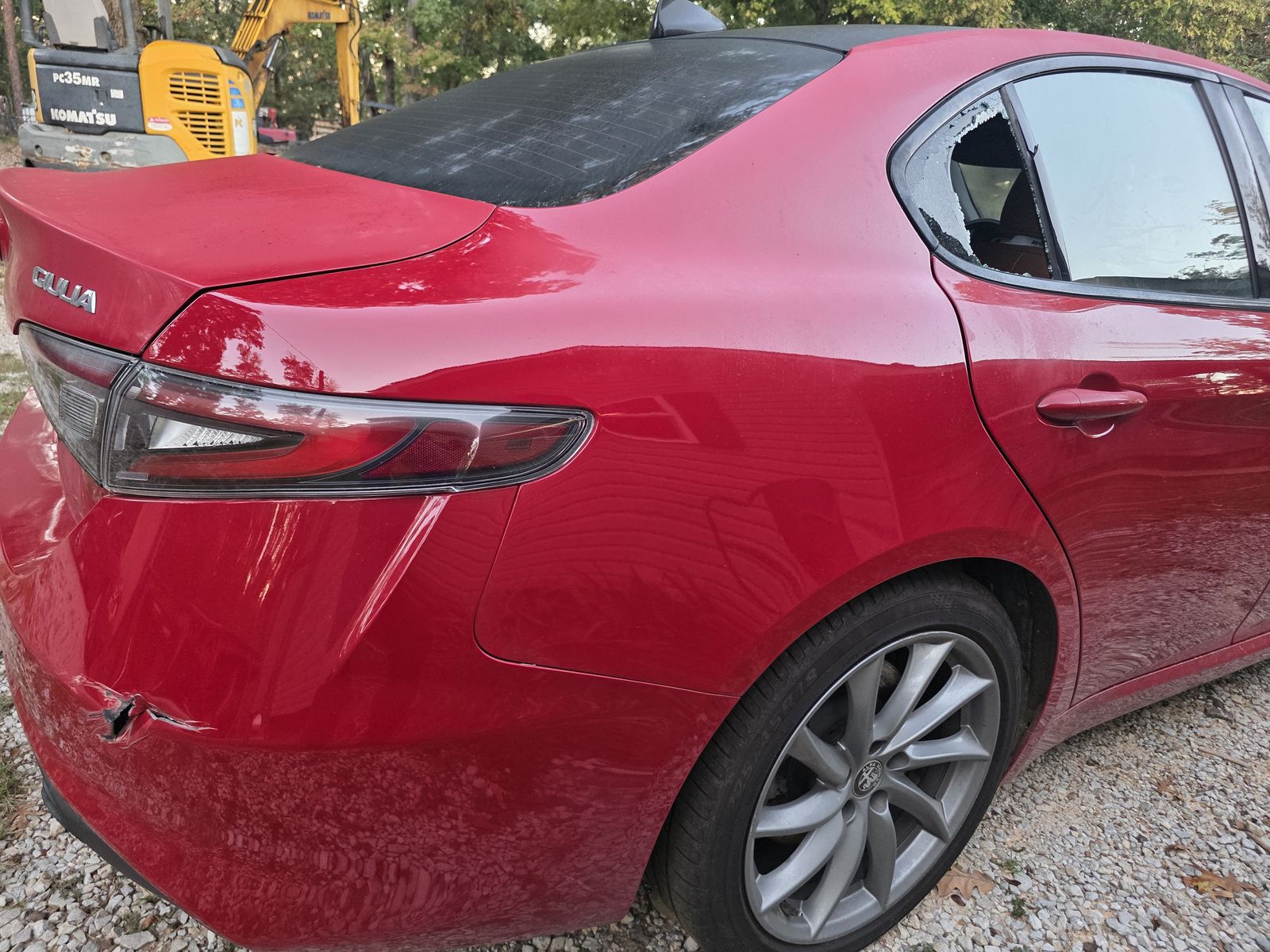 Rear quarter of the red Alfa Romeo Giulia with a punctured bumper cover and shattered quarter glass